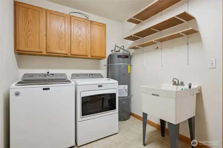 Kitchen leads into laundry room with extra storage and utility sink