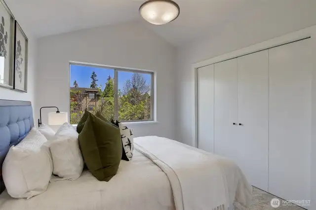 Upstairs, two bedrooms both boast vaulted ceilings and custom Elfa closet storage systems.