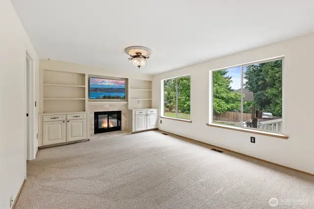 Custom built-ins flank the beautiful stone encasing the gas fireplace. Enjoy the beautiful view out the large picture windows, overlooking the backyard.