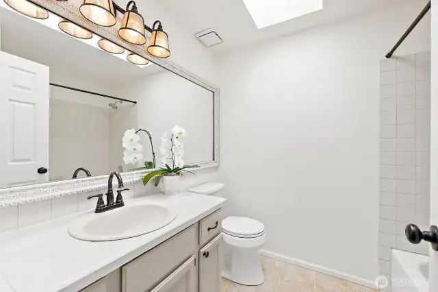 Skylight floods this upstairs shared bathroom with tons of natural light.