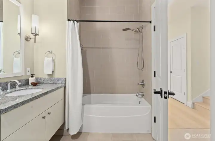 Full bathroom on the main level with a clean modern look and cozy soaking tub.
