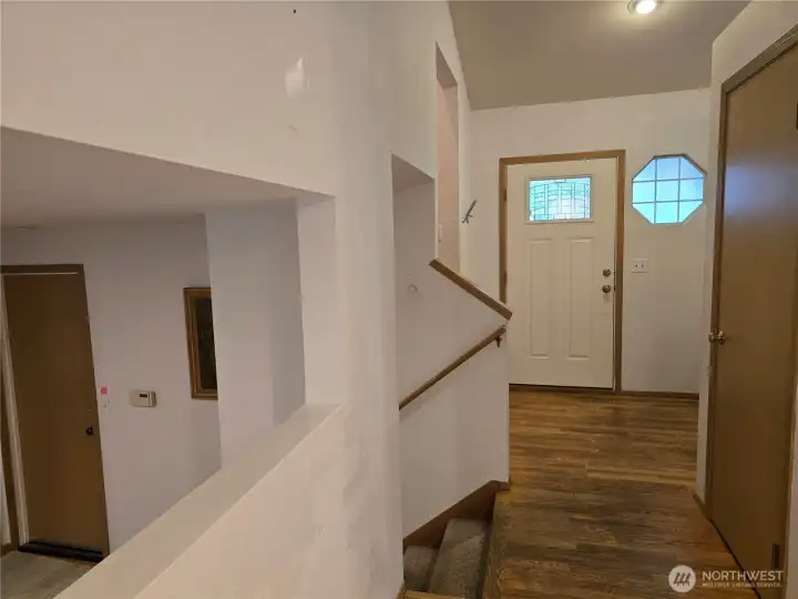 View from kitchen eating area toward front entrance of home, with galley opening to the family room on left. Stairs to upstairs also on the left.