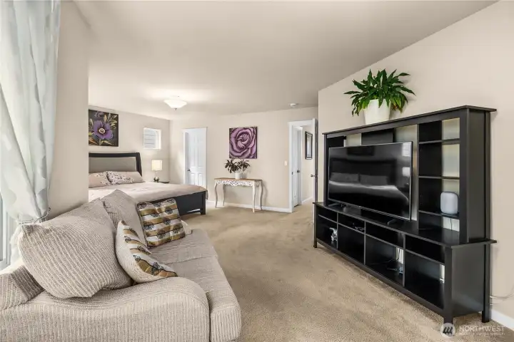 Spacious light filled primary bedroom with sitting area, en suite bath and two walk in closets.