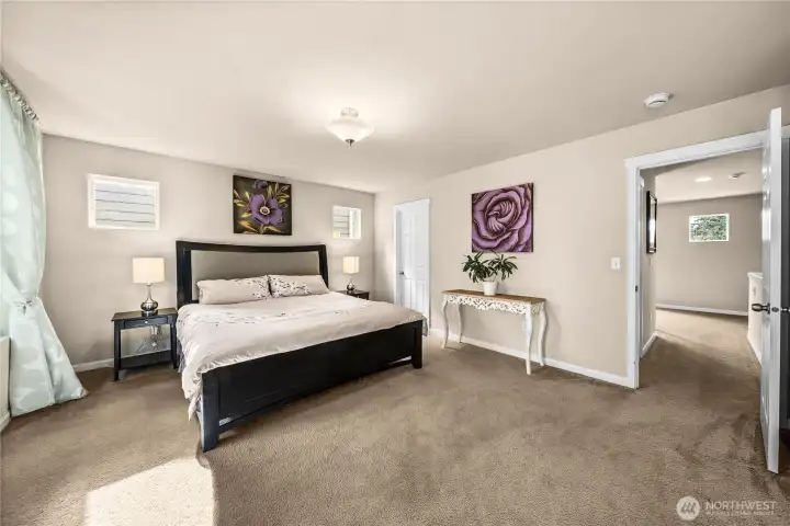 Spacious light filled primary bedroom with sitting area, en suite bath and two walk in closets.