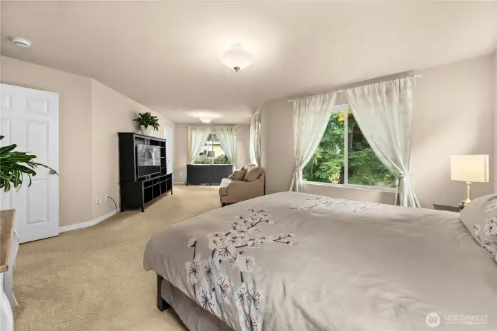 Spacious light filled primary bedroom with sitting area, en suite bath and two walk in closets.