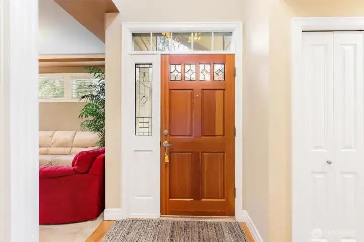 Entry door with leaded glass panel and transom window above adds architectural character and brings in natural light.  One of the many closets on the right side of this photo.