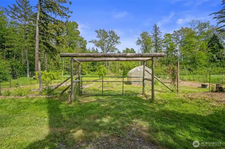 Gated and fenced orchard and garden area with green house.