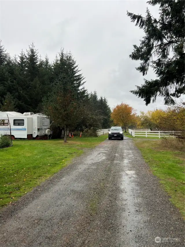 Facing down the gravel road going toward the property. This vacant land is on the right. It is  just before the residence at the end with the vinyl fence.