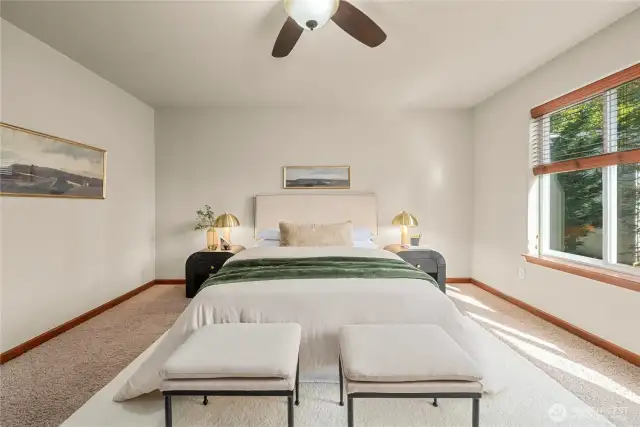 The primary bedroom offers views of the back yard and trees.