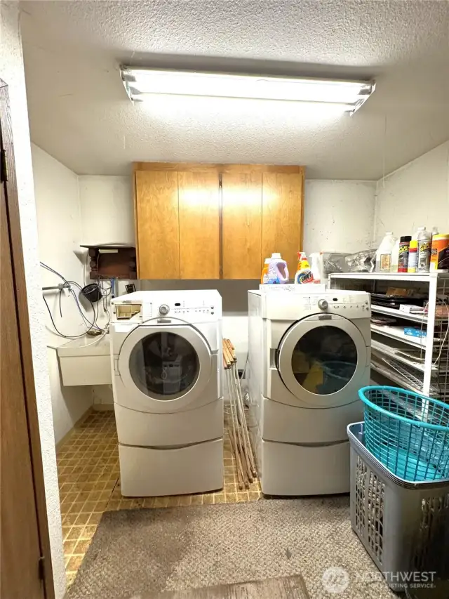 Laundry room w/ folding area, a closet, sink and water heater.