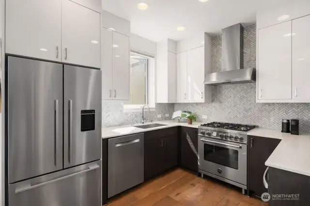 The kitchen, a bright and happy place to cook: reflective high gloss cabinetry reaches the ceiling for extra storage, "White Ice" quartz countertops, honed Carrara marble herringbone backsplash, full application.  Top quality appliances noted in the next photo.