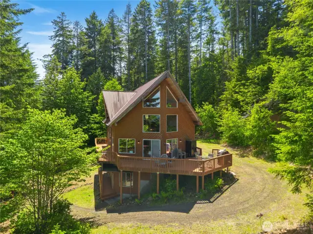 Expansive windows frame scenic views of the fjord and forested landscape.