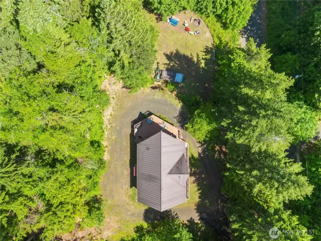 Bird’s-eye view shows the home nestled among mature trees with a functional wrap-around driveway.