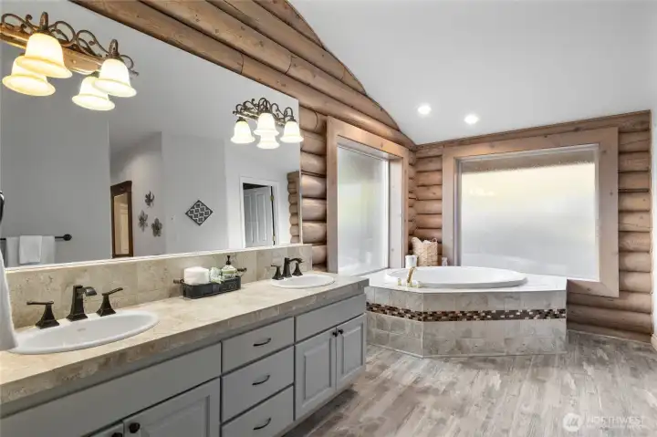The primary bathroom boasts a double sink vanity, a spacious soaking tub, a separate shower area, and a large walk-in closet.