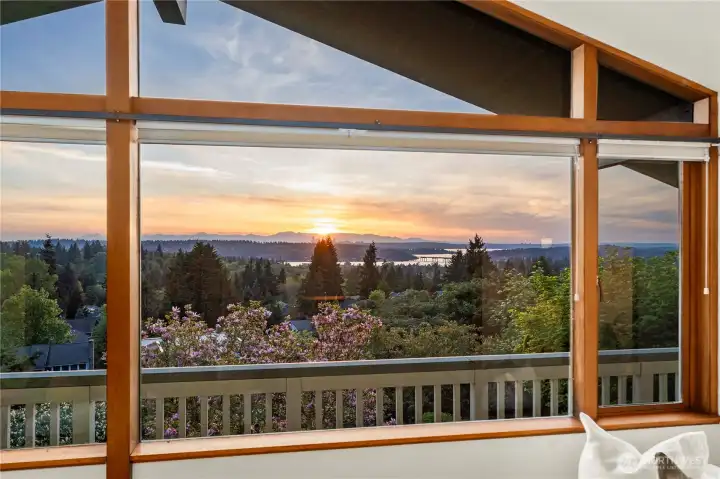 A wide-angle view overlooking the lake as the I-90 bridge stretches toward the sun-drenched towers of Bellevue and the iconic Seattle skyline.