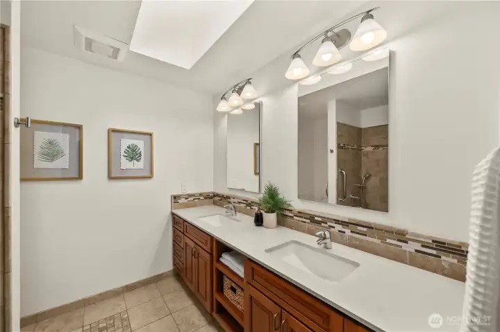 Hallway bathroom with skylight, dual vanities and a full bath