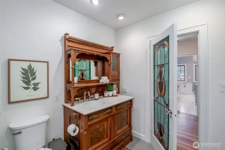 The main floor 3/4 bath features an antique piece turned into a sink. The right cupboard is the laundry shoot!