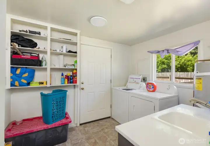 Laundry room offers built-in storage, workspace, and access to the backyard.