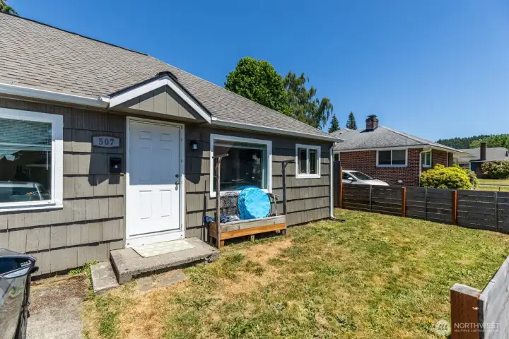 Exterior view highlighting the unit's private entrance and usable yard space.