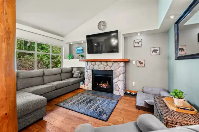This cozy yet roomy living room is perfect for any gathering whether you are entertaining or just nestling up to the river rock gas fireplace featured here.  Check out the hardwood floors and wood pillars here!