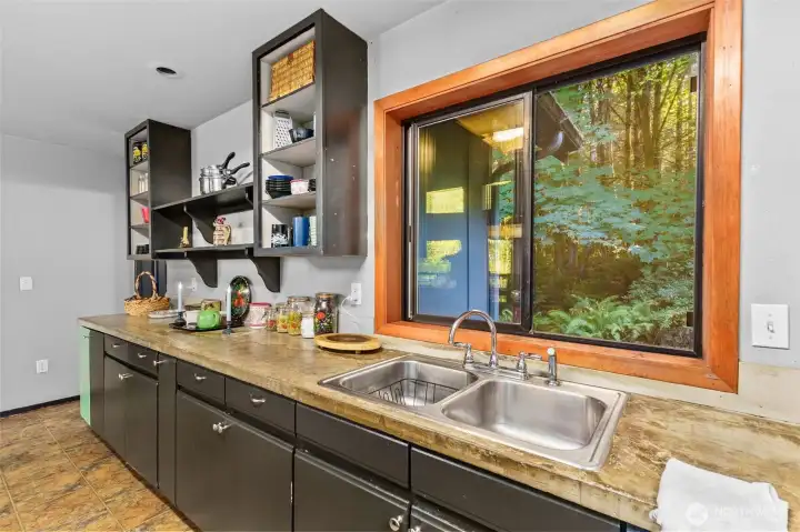 Open kitchen with double sink looking out over the wooded setting
