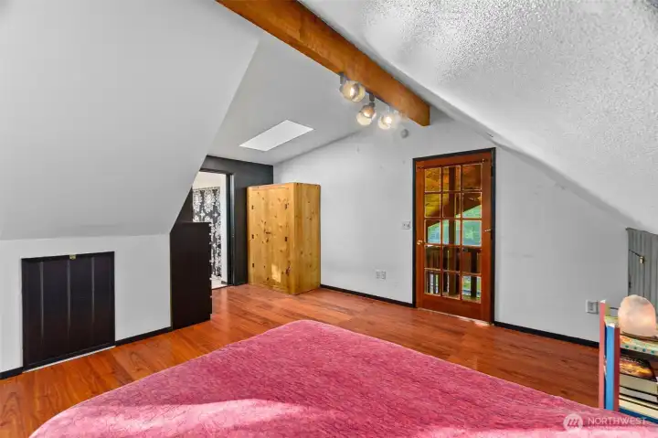 Door to ensuite bath and wood door leading to private balcony overlooking the wooded setting