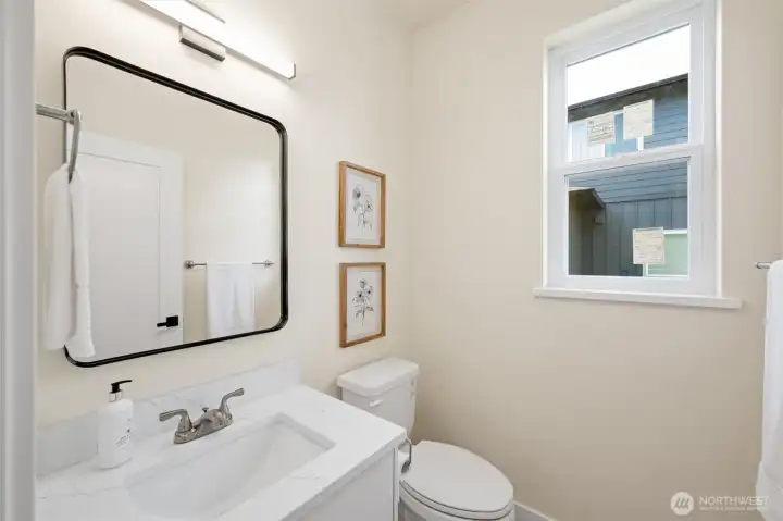 Main floor half bath just off the kitchen area, next to the garage entry.