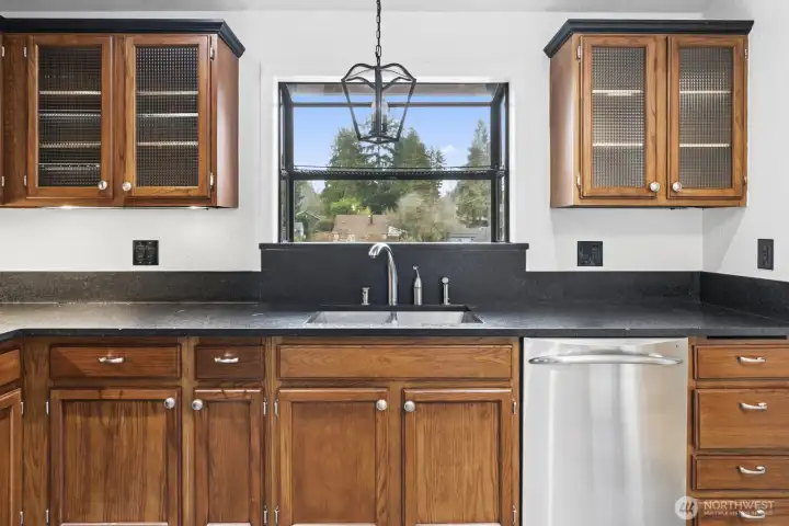 Sun-filled kitchen features a garden window perfect for herbs and plants, with a chandelier adding warmth and extra light.