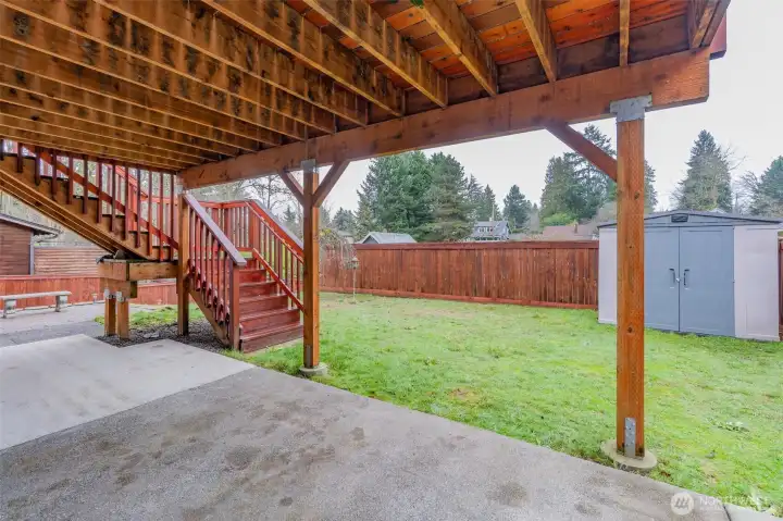 Covered patio with deck stairs in the background, ideal for gatherings and entertaining.