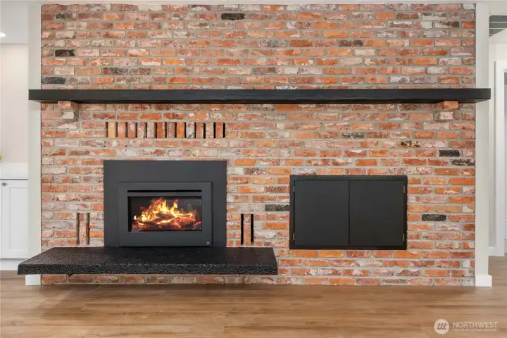 Gorgeous brick surround for the gas fireplace has wood slab mantle and built-in cupboard.