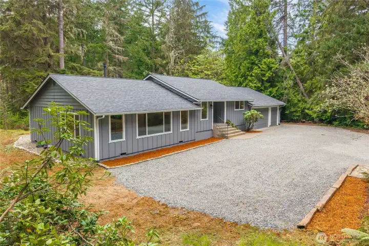 Showing the front of the house from a higher elevation. RV parking is possible on either side of the home. The right side has backyard access for vehicles and a path to the well.