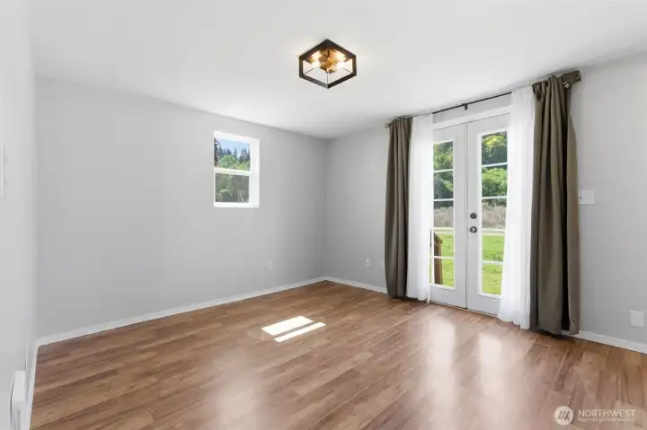 Primary bedroom facing French doors leading to a back deck