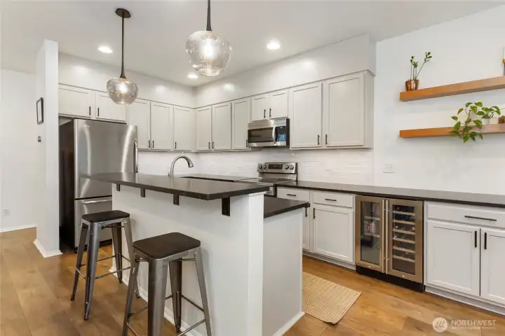 Entertainer-friendly kitchen highlight featuring a built-in wine and beverage fridge, perfectly integrated beneath the granite countertops for easy access and stylish storage. The revere pewter colored cabinetry, stainless steel appliances, and modern pendant lighting create a polished look, while the dedicated beverage station adds a touch of luxury ideal for hosting and everyday enjoyment.