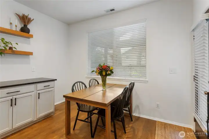 Spacious dining area offering ample room for a full-size dining table, illuminated by natural light from the large window. Durable LVP flooring and clean, modern finishes create a welcoming setting for everyday meals or hosting guests, with easy flow to the kitchen for effortless entertaining.