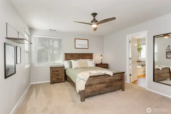 Very large primary bedroom suite offering generous space for a king-size bed and additional seating or storage. Soft carpeting, abundant natural light, and a ceiling fan create a comfortable retreat. The bedroom connects directly to an adjacent en-suite bath and a spacious walk-in closet, providing convenience, privacy, and a true primary-suite feel.