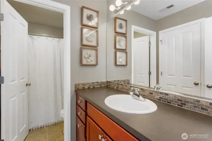 Jack-and-Jill bathroom designed for privacy featuring separate access from both bedrooms, a spacious vanity with ample counter space, and bright lighting. The layout includes a private enclosed toilet area and a tub/shower combination, allowing multiple users to comfortably share the space while maintaining privacy and functionality.