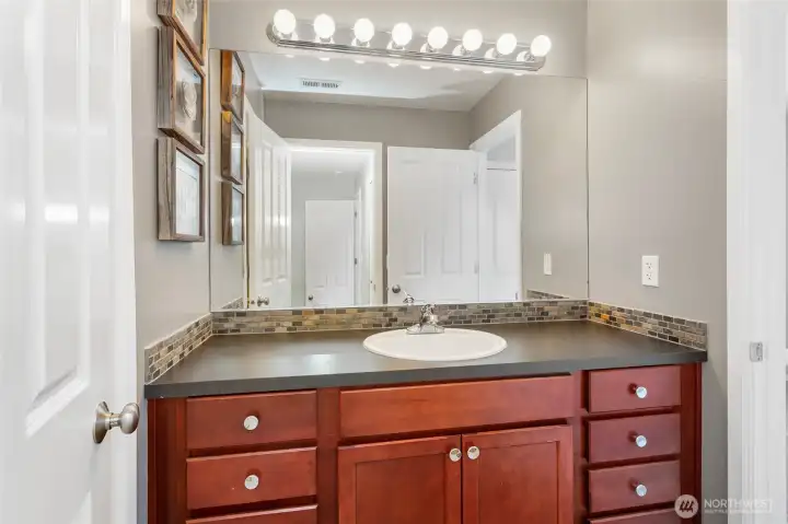 Jack-and-Jill bathroom designed for privacy featuring separate access from both bedrooms, a spacious vanity with ample counter space, and bright lighting. The layout includes a private enclosed toilet area and a tub/shower combination, allowing multiple users to comfortably share the space while maintaining privacy and functionality.