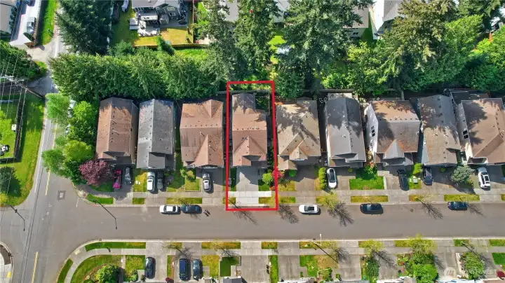 Aerial view highlighting the home’s prime location within the desirable Acadia community, featuring tree-lined streets and a welcoming neighborhood layout. Residents enjoy close proximity to the community playground and open play field—perfect for outdoor recreation, gathering, and everyday enjoyment just steps from home.