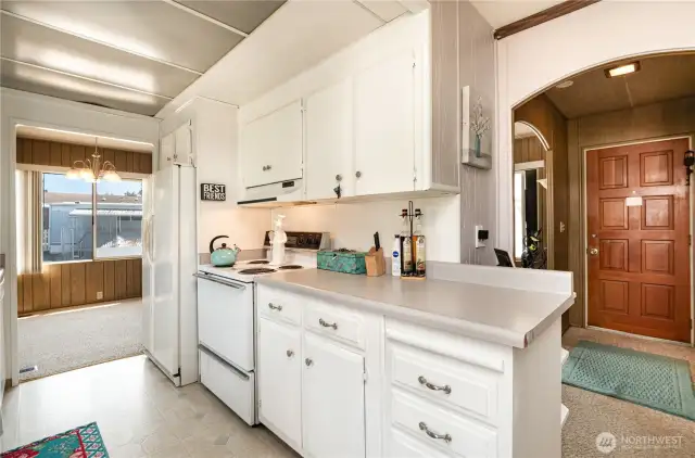 Kitchen features bright cabinetry and matching white appliances.