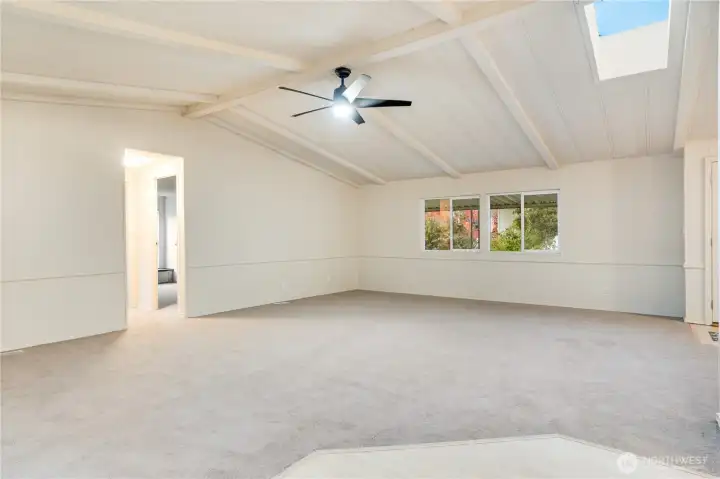 Another angle shows the skylight bringing in natural light, complemented by a new ceiling fan for comfort. Plush new carpet with 8lb padding and vapor barrier adds a soft touch underfoot.