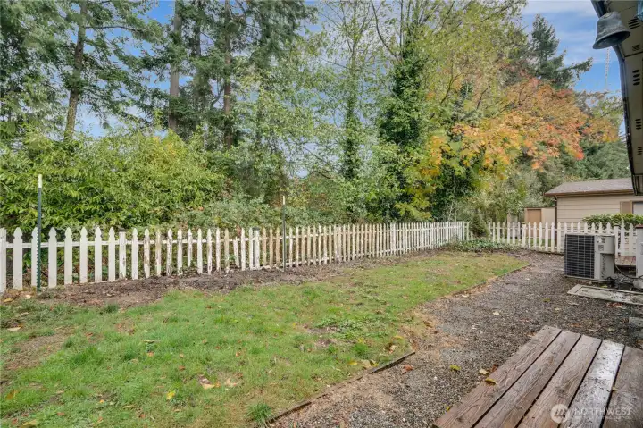 The yard backs up to lush greenery, adding privacy and a beautiful natural backdrop.