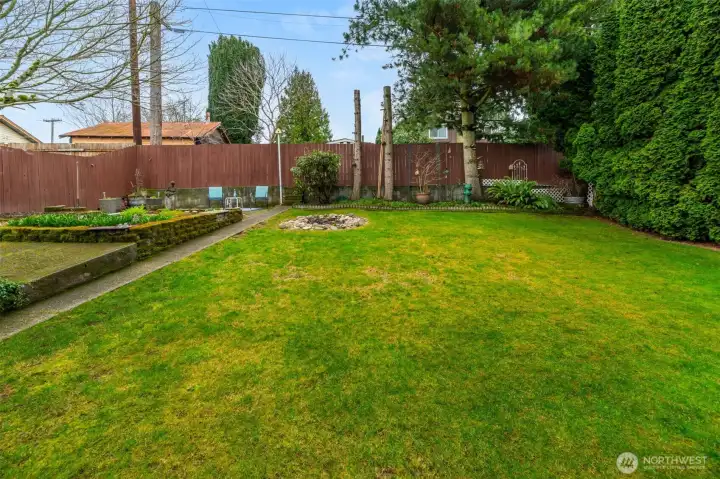 Fully fenced back yard with garden area and fire pit.