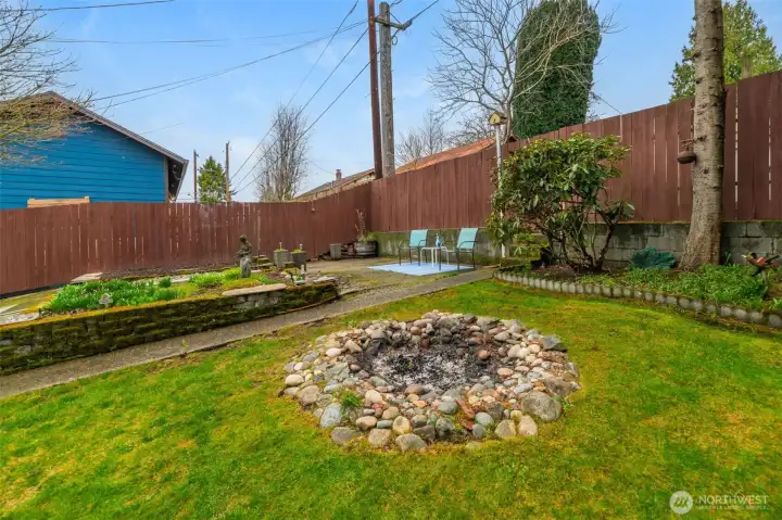 Fenced rear yard with garden space, alley access and huge fire pit for outdoor gatherings.