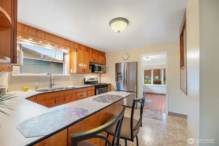 Classic kitchen design with breakfast bar, gas cooktop, tons of cabinet space.  The window above the sink gives plenty of light to make this kitchen feel warm and inviting.