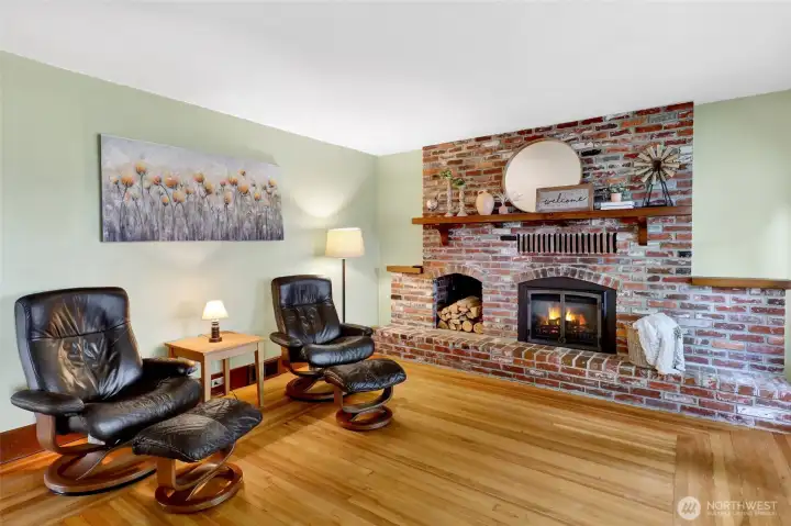 A cozy, crackling fireplace with a beautiful brick surround anchors the room, complete with a unique exterior hatch for convenient firewood access.