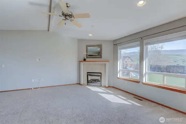 Bright living room featuring large windows, abundant natural light, and cozy propane fireplace for year-round comfort.