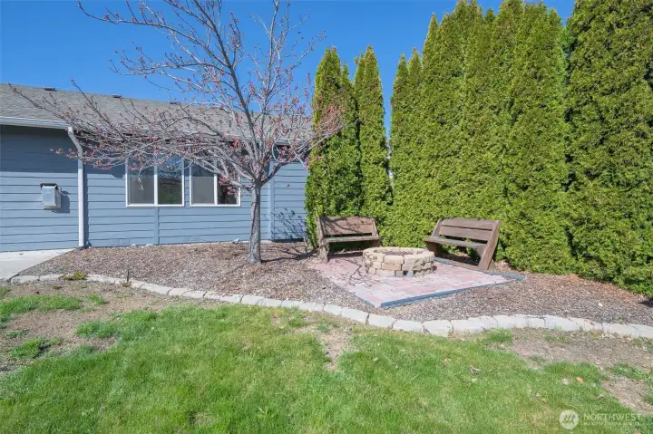 Backyard designed for entertaining with built-in propane fire pit and gathering space.
