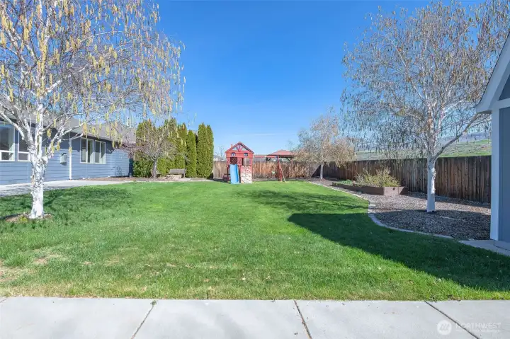 Well-maintained backyard with multiple functional spaces for entertaining, relaxing, and recreation.