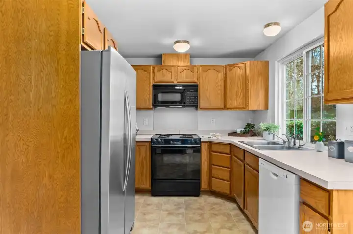 Kitchen with Oak cabinets, electric cook-top, dishwasher, double sink overlooking rear yard, and stainless steele refrigerator.