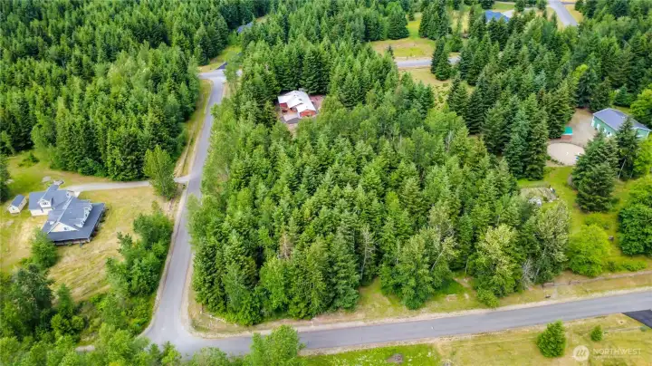 This home is located on two corners, wooded for privacy, trails.  Center house, red in color